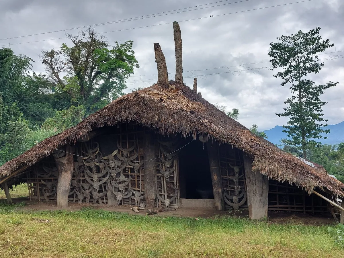 A thatched house with a carved wooden façade in a hill village