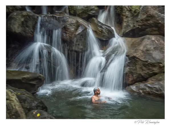 A bather in the waterfall pool at the Double Decker Living Root Bridge