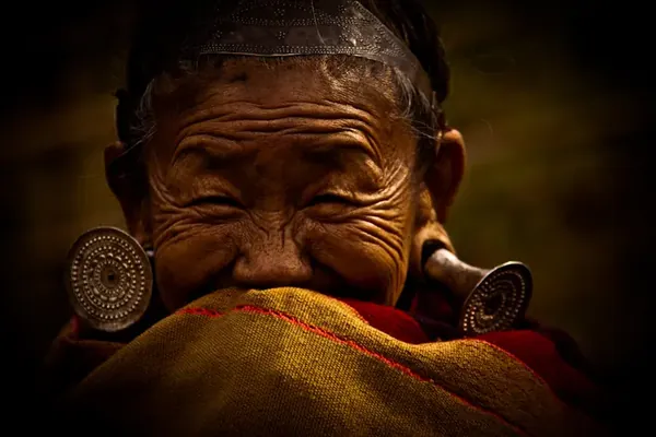 A laughing elder wearing large ear ornaments