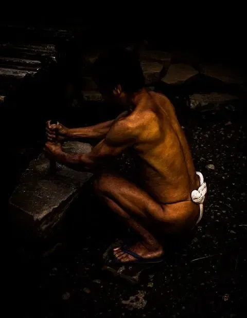 A man crouching in a dark interior