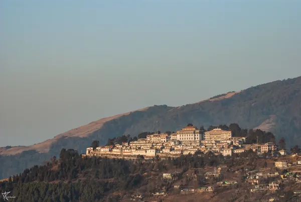 A monastery spread along a hilltop above forested valleys