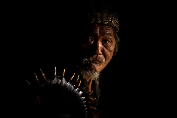 Portrait of an Igu, a traditional priest, lit softly against a dark background