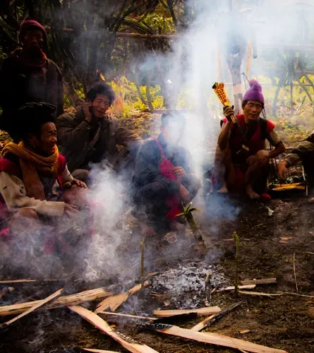 Villagers gathered around a smoking fire during a ritual